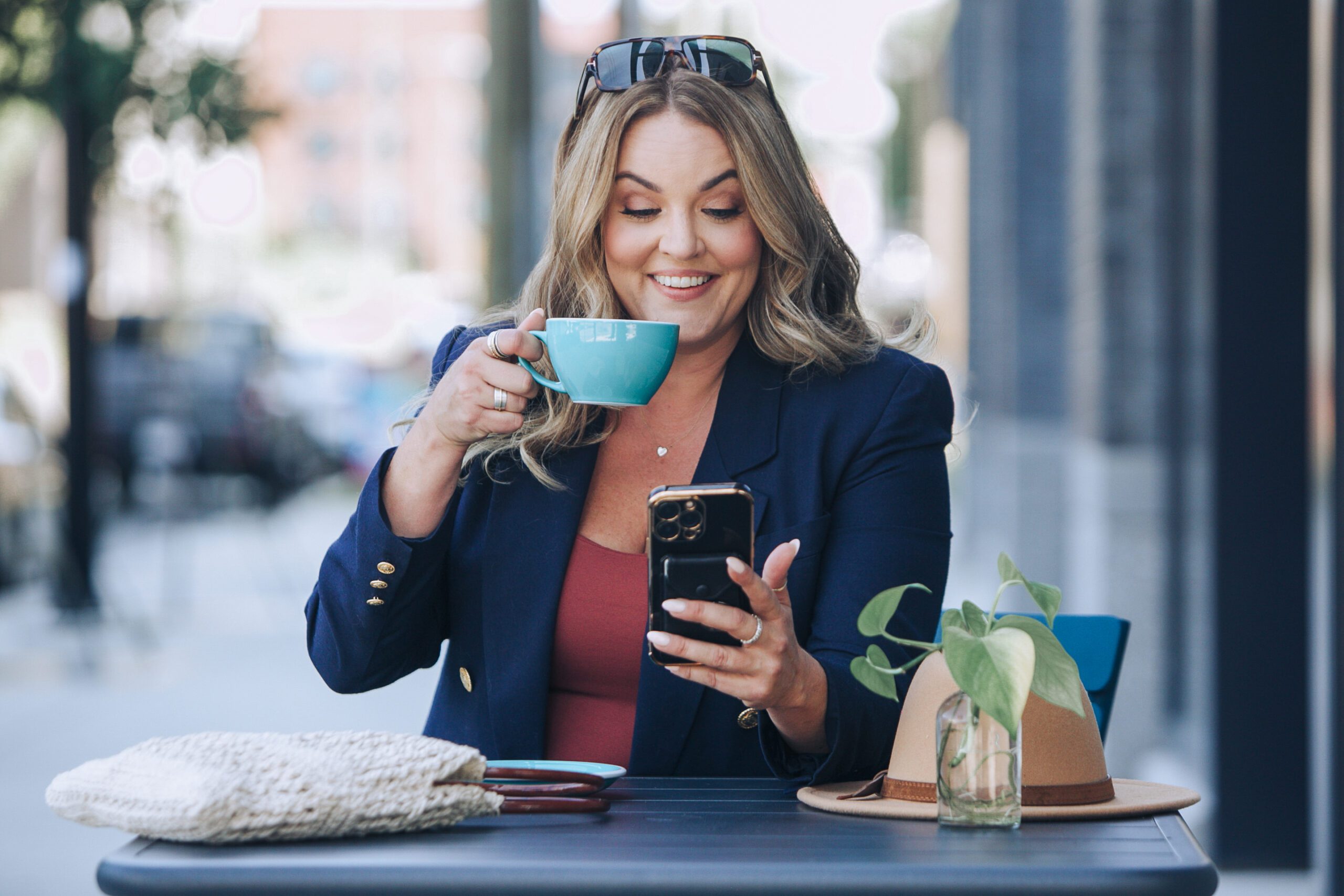 Businesswoman at a cafe checking her phone with a coffee cup in hand