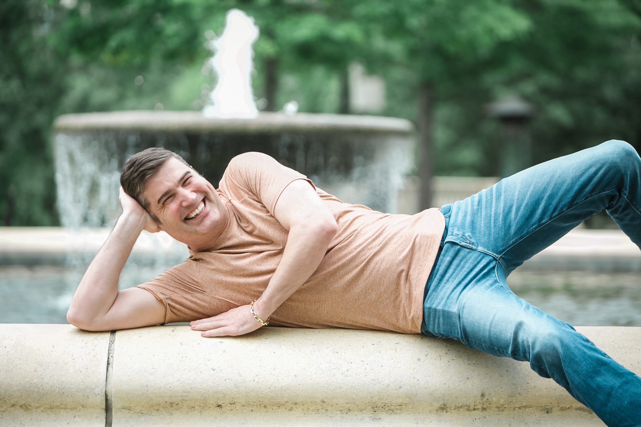 Joyful man lying down near a fountain in a park