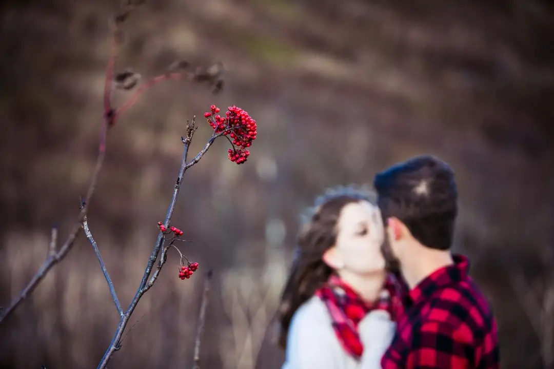 couple kissing pose with red flowers