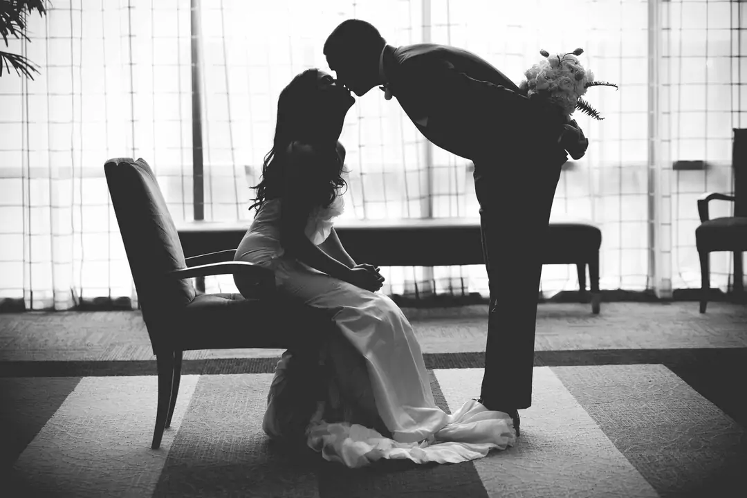 bride sitting on chair and groom kissing to bride