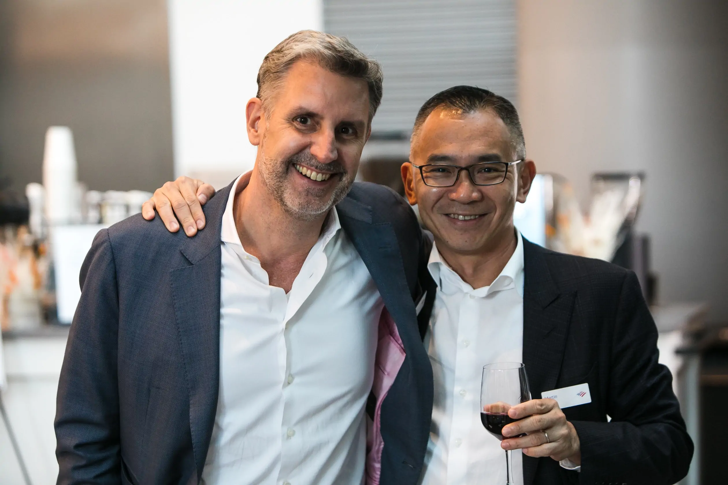 two businessmen with red wine glass and smiling face